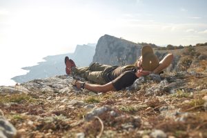 traveler-rests-lying-top-mountain-rays-setting-sun